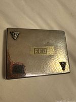Front of hammered sterling silver cigarette case showing monogram and corner ornaments
