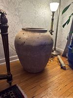 Full view of large terracotta pot beside lamp