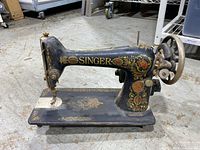 Left side view of Singer sewing machine showing ornate decals and overall wear
