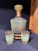 front view of green textured decanter with two shot glasses