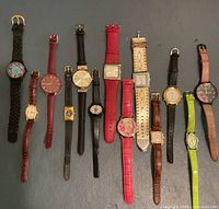 All thirteen watches laid out side by side on dark surface