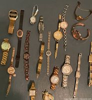 Overall group of 18 metal-band wristwatches displayed on flat surface