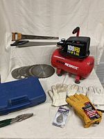 Group shot of air compressor, saw blades, backsaw, square, rotary tool case, gloves, snips