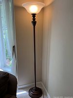 Full view lit torchiere floor lamp next to wall