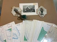 Overview of all items: glass float, two plaques, maritime print, spread of nautical charts
