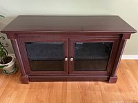 Front view of dark cherry laminate media cabinet with glass doors