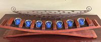 wooden votive holder with seven blue candles and metal canoe displayed together