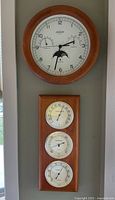 Clock and three-dial weather panel mounted on wall