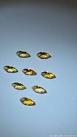 Nine marquis cut golden citrine gemstones arranged on a white background showing their color and clarity