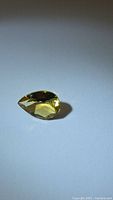 Photo of pear-shaped natural golden citrine gemstone on a plain white background showing color and cut