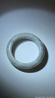 Top-down view of light green jade ring showing its smooth, polished round surface and consistent coloration with natural markings.