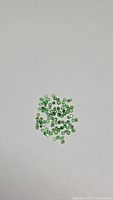 Photo showing loose natural tsavorite garnet gemstones spread out to show size and quantity.
