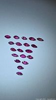 Photo taken showing 21 marquis cut rubies with a deep red color arranged on white background.