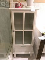 Front view of closed cabinet showing glass door and drawer