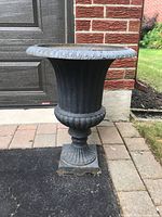 Full view of cast iron pedestal planter in driveway