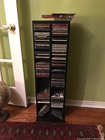 Full view of black CD tower shelf with CDs