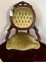 Front view showing carved frame and green tufted upholstery