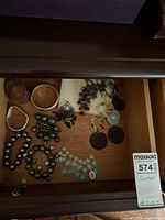 Drawer with assorted bracelets, earrings, necklace visible