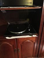 Front view of Denon DP-300F turntable on shelf with dust cover open