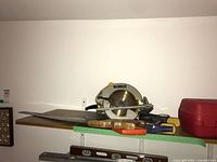 Shelf with DeWalt circular saw, hand saw, chisels, clamp, and level