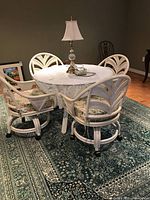 Group of four white rattan rolling chairs around table