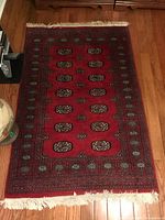 Full view of red Bokhara rug with fringe