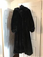 Front view of full-length mink coat hanging on door