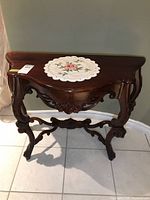 Front view of ornate demilune table with doily