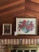 Both framed needlepoint artworks on fireplace mantel