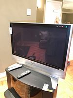 Front view of Panasonic 37" plasma TV on stand with remote
