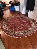 Full view of round red floral area rug on hardwood floor