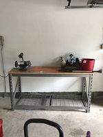 Front view of steel framed workbench with wood top and lower wire shelf