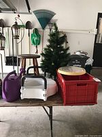 Wide view showing watering can, seat riser, red crate tote, wooden stool, artificial Christmas tree