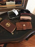 All items on table: two wallets, two eyeglass cases with glasses, eyeglass chain