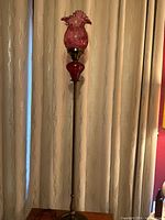 Full view of floor lamp showing metal column, red glass shade and accent