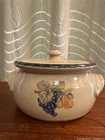 Front view of stoneware casserole with lid showing fruit motif