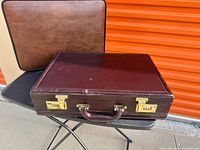 Burgundy attaché on top of black bag, brown attaché behind