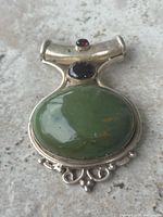 Front view showing green, black and red stones and silver setting