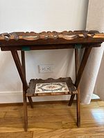 Full view of wooden tray on folding stand against wall