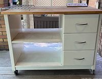 Front view showing butcher-block top, drawers, shelves, and casters