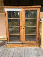 Front view of oak cabinet with glass doors and taped lower panels