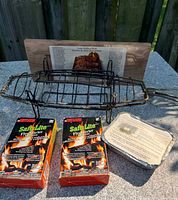 all lot items grouped: fish basket, cedar plank, two fire starter boxes, tin of wood chips
