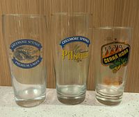 Front view of three branded beer glasses showing logos