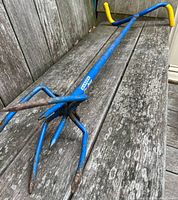 Full view of blue Garden Claw cultivator on wood surface