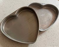 Two heart-shaped metal cake pans nesting together, interior view showing finish and wear