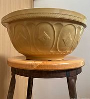 Side profile of yellow stoneware bowl on stool