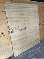 Front view of partial plywood sheet leaning against full sheet