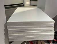 Stack of six white MDF shelves showing edges and finish