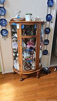 Front view of oak curved glass curio cabinet filled with collectibles