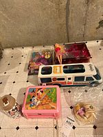 Group shot of camper, boxed doll, loose doll, tin, lunch box, thermos, bagged small items